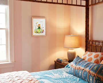 Nature at Play botanical wall art in an oak frame, styled on a warm bedroom wall beside a bedside lamp.