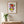 Heart in Bloom botanical wall art print in a red oak frame, shown in a calm neutral room