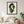 The Celery Woman print in a black frame hanging in a living room