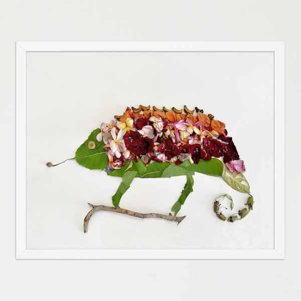 Reclining chameleon formed from broad green leaves, colorful petals, and a curled vine tail on white. Botanical wall art by FloraFusion.