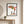 Reaching for Autumn art in a black frame in an entryway