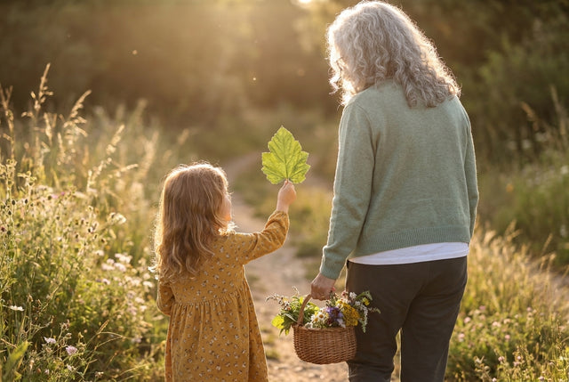 Grandmother and granddaughter collecting leaves and flowers on a golden hour trail